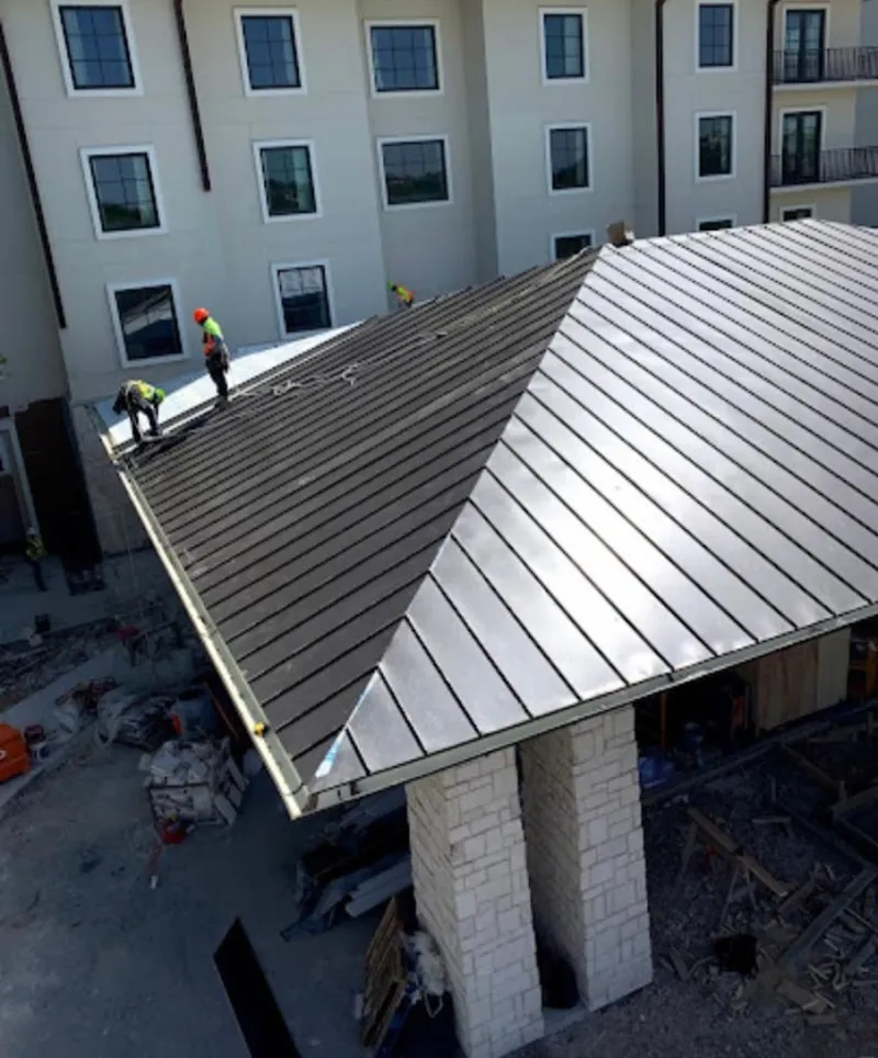 Crew installing standing seam metal roof panels on a commercial project in Tredyffrin